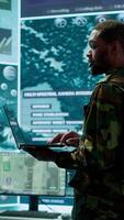 Vertical Military officers work in a high tech army control tower base, managing surveillance imagery from cctv satellite. Soldiers handle data protection to ensure national security. Camera A. video