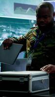 Vertical Military officer in a high tech control center engages in cybersecurity operations, protecting classified data from threats and managing digital warfare strategies to maintain state secrets. Camera A. video