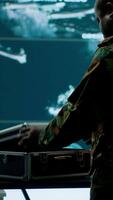 Vertical Army espionage specialist in a control center collecting satellite cctv data real time surveillance, strategic military operations. Working to ensure national security and protocols. Camera A. video