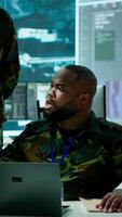 Vertical Military personnel in a modern command center handle critical information, collecting live surveillance data to maintain security protocols. Team of army crew working on reconnaissance. Camera A. video
