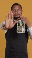 Vertical Waiter in uniform showing a stop sign with his palm raised in studio, expressing negative symbol and refusal about something. Showing rejection and being dissatisfied. Camera B. video