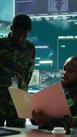 Vertical Angry army expert in a command post power base monitors satellite footage, yelling at soldier and throwing papers. Frustrated officer looks at real time data for operational success. Camera B. video