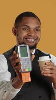 Vertical Professional friendly waiter showing the pos terminal with a credit card, symbolizing electronic payments for a meal. Restaurant employee works in a service oriented industry. Camera A. video