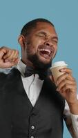 Vertical Hotel concierge staff drinks coffee while he is yawning and feeling tired, trying to get more energy with the caffeine beverage. Doorkeeper employee is exhausted and fatigued. Camera A. video