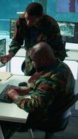 Vertical Military staff in a modern operations hub handling critical information collected on satellite systems, real time data helping support field missions. Army protocols for national security. Camera B. video