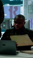 Vertical In a high tech military office, soldiers team analyze real time data collected by surveillance system. Staff interpret intelligence and coordinate operations to ensure national defense. Camera A. video