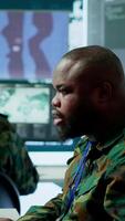 Vertical Military team in a control center uses advanced technology to gather crucial information, satellite surveillance systems to support strategic planning. Potential threats on big screen. Camera A. video