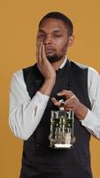 Vertical Restaurant employee dealing with a painful headache while he serves clients, carrying a cruet set for excellent customer satisfaction. Unwell waiter in pain with migraine. Camera B. video