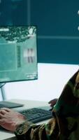Vertical Team of military specialists overseeing surveillance activity by using a cctv footage and radar, pointing at a big screen and world map. High tech control center base of operations. Camera A. video