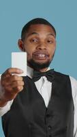 Vertical Bellhop personnel offering access card to the room for guests, presenting the key after check in procedure. Hotel porter employee providing lodging and five star amenities at the resort. Camera A. video