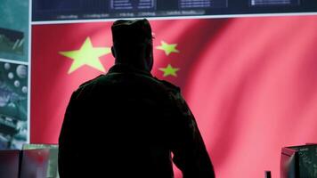 Chinese military officer analyzing information on big screen in a command center base of operations. Chinese flag running on display while soldiers inflict fear through fake news, national security. Camera A. video