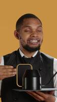Vertical Restaurant staff serving clients with tea before their dinner order, bringing the teapot at the table. Waiter dressed in apron serves customers for satisfaction, service oriented industry. Camera A. video