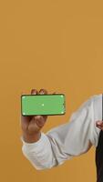 Vertical Waiter with professionalism holding a phone with isolated mockup display, working in dining and eatery industry. Friendly restaurant staff does customer oriented activity at his job. Camera A. video