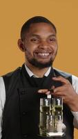 Vertical Professional waiter with apron presenting tablet with isolated mockup, presenting the copy space while he carries the cruet set. Skilled catering staff works in customer service at diner. Camera A. video