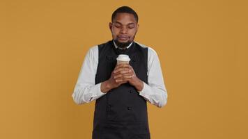 Cheerful waiter drinking a cup of coffee and relaxing after serving clients, working in catering and service oriented industry. Restaurant staff enjoying a caffeine refreshment. Camera B. video