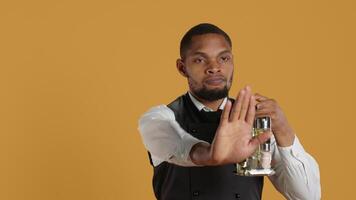 Waiter in uniform showing a stop sign with his palm raised in studio, expressing negative symbol and refusal about something. Showing rejection and being dissatisfied. Camera A. video