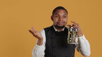 Waiter shrugging while he carries a cruet set with condiments, acting uncertain and showing i dont know symbol in studio. Professional customer focused staff is confused and unsure. Camera A. video