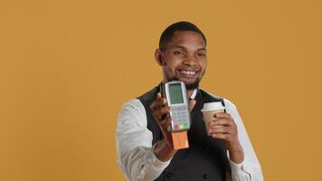 Professional friendly waiter showing the pos terminal with a credit card, symbolizing electronic payments for a meal. Restaurant employee works in a service oriented industry. Camera A. video