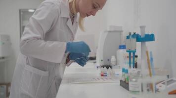 Laboratory determination of blood type. Blood test. Female laboratory assistant makes blood test, blood samples placed in cells on chart to determine the group and Rh factor. Recipient and donor. video