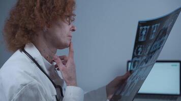 Mature caucasian woman doctor radiologist examining CT scan of patient's chest and lungs with Covid-19 in hospital office. Medical diagnosis concept. computed tomography of the lungs video