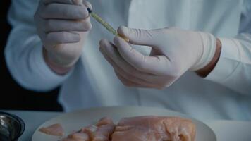 Genetic injection into raw chicken meat. Scientist doing injection to pieces meat. Lab assistant testing GMO chicken. Worker of food quality control. Genetically modified antibiotics residue in food. video