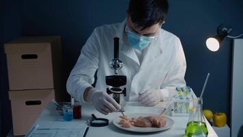 Food quality control concept. Lab assistant testing GMO chicken. Scientist examining sample meat, syringes with anabolic and antibiotics, microscope in laboratory. Food bio engineering process. video