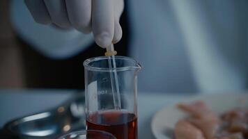 Genetics laboratory technician takes red liquid from a glass vial with pipette and applies it to chicken fillet. GMO test laboratory. Genetically modified meat. DNA. Nutrition expert testing food. video