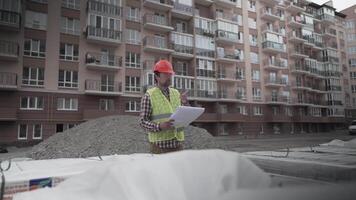 An innovative supervisor in construction in helmet and wearer checks materials and checks quantity against the documents at the construction site of a residential building. Building inspector at work. video