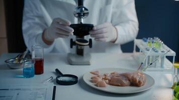 Food quality control concept. Lab assistant testing GMO chicken. Scientist examining sample meat, syringes with anabolic and antibiotics, microscope in laboratory. Food bio engineering process. video
