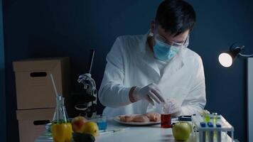 Genetics laboratory technician takes red liquid from a glass vial with pipette and applies it to chicken fillet. GMO test laboratory. Genetically modified meat. DNA. Nutrition expert testing food. video