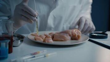 Hands male laboratory technician injects syringe into meat fillet chicken for GMO research. Genetically modified meat. Scientist injecting GMO into meat. Experiment with organic nutrition supplements. video