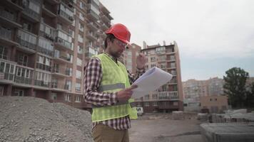 An innovative supervisor in construction in helmet and wearer checks materials and checks quantity against the documents at the construction site of a residential building. Building inspector at work. video