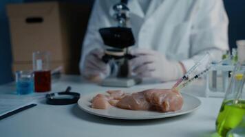 Food quality control scientist works with microscope in laboratory. Syringes with antibiotics in raw meat, injections with genetically modified organisms in chicken, drugs and chemicals in food. video