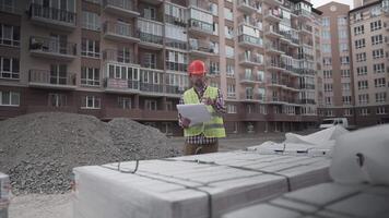 An innovative supervisor in construction in helmet and wearer checks materials and checks quantity against the documents at the construction site of a residential building. Building inspector at work. video