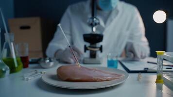 Lab assistant testing GMO chicken. Worker of food quality control examines samples behind a microscope. Genetically modified antibiotics residue in food. Food technology. Food quality control concept. video