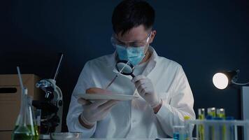 Laboratory assistant with magnifying glass examining raw meat. Detection of poison. Scientist testing GMO chicken in chemical lab. Man looking at meat sample though magnifying glass, product quality. video