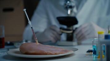 Food quality control scientist works with microscope in laboratory. Syringes with antibiotics in raw meat, injections with genetically modified organisms in chicken, drugs and chemicals in food. video