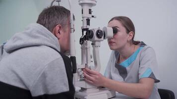 Ophthalmologist and patient testing eyesight. Man doing eye test with optometrist. Ophthalmologist using apparatus for eye examination in clinic. Doctor examining patient doing eyesight measurement. video