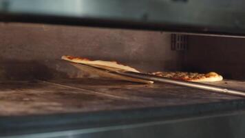 Cook turns the finished pizza in a hot oven. Close-up video