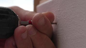 A man hands using a power tool fastens a board with a screw. Slow motion video