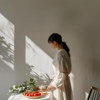 A woman in casual linen outfit standing cooking with vegetables and tomatoes on the table photo