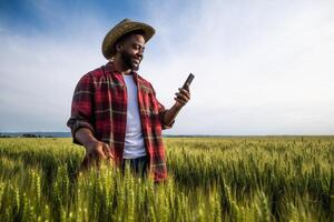 Young farmer using mobile phone while standing in his growing wheat field. photo