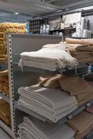 The textile products are folded on shelves in the store. In the store, neatly folded home interior goods are displayed on the shelves. photo