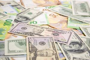 A scattering of US dollar bills and Euro banknotes on a white surface photo