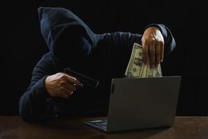 Hacker spy man one person black hoodie sitting hand holding credit card look computer laptop used login password attack security data digital internet network system night dark background copy space photo