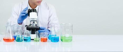 Portrait asian man student scientist wearing a doctor gown in the lab looking hand at chemist. caused by mixing reagents in scientific research laboratories with test tubes and microscope on the table photo