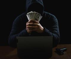 Hacker spy man one person black hoodie sitting hand holding credit card look computer laptop used login password attack security data digital internet network system night dark background copy space photo
