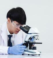 Portrait asian man student scientist wearing a doctor gown in the lab looking hand at chemist. caused by mixing reagents in scientific research laboratories with test tubes and microscope on the table photo