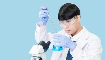 Asian man student scientist in reagent mixing laboratory In a science research laboratory with test tubes of various sizes. on the floor in laboratory chemistry lab blue background. photo