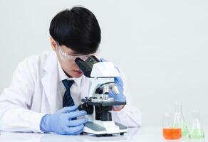 Portrait asian man student scientist wearing a doctor gown in the lab looking hand at chemist. caused by mixing reagents in scientific research laboratories with test tubes and microscope on the table photo